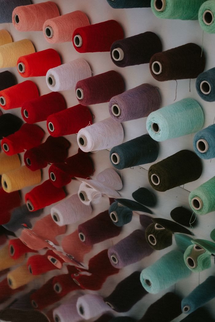 Services A vibrant collection of colorful yarn spools perfectly aligned on display indoors.
