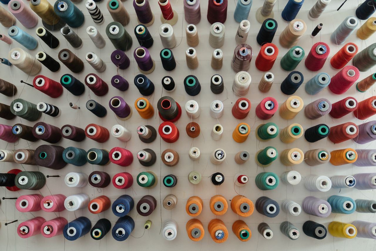 Services A top-down view of assorted colorful thread spools organized neatly for sewing projects.